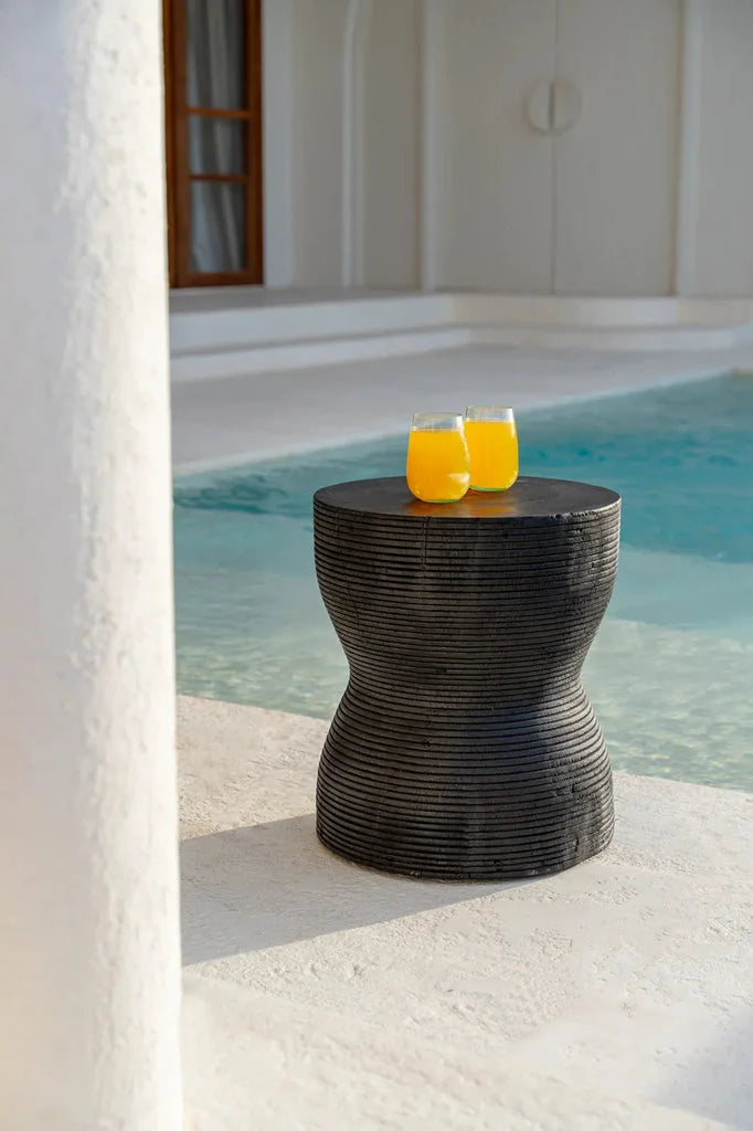 Table d’appoint noire en forme de sablier avec deux verres de jus d’orange