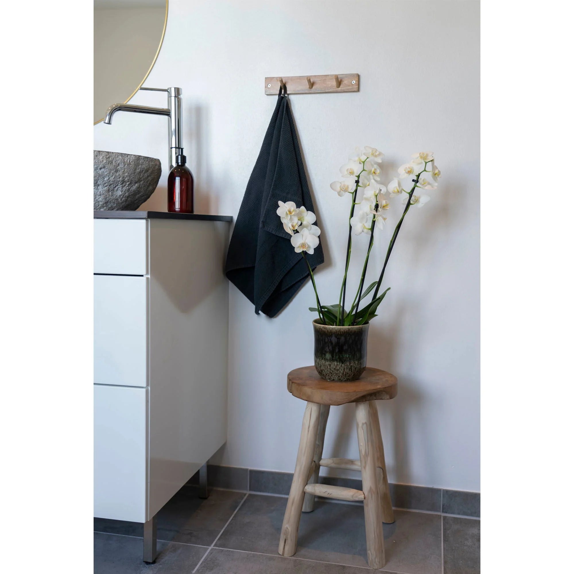 Coin de salle de bain avec vanité, tabouret rond en teck massif et orchidée