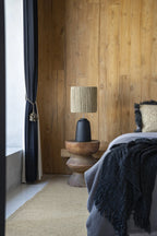 Abat-jour tissé sur une base sombre avec le tabouret sculptural en bois de Suar brun naturel