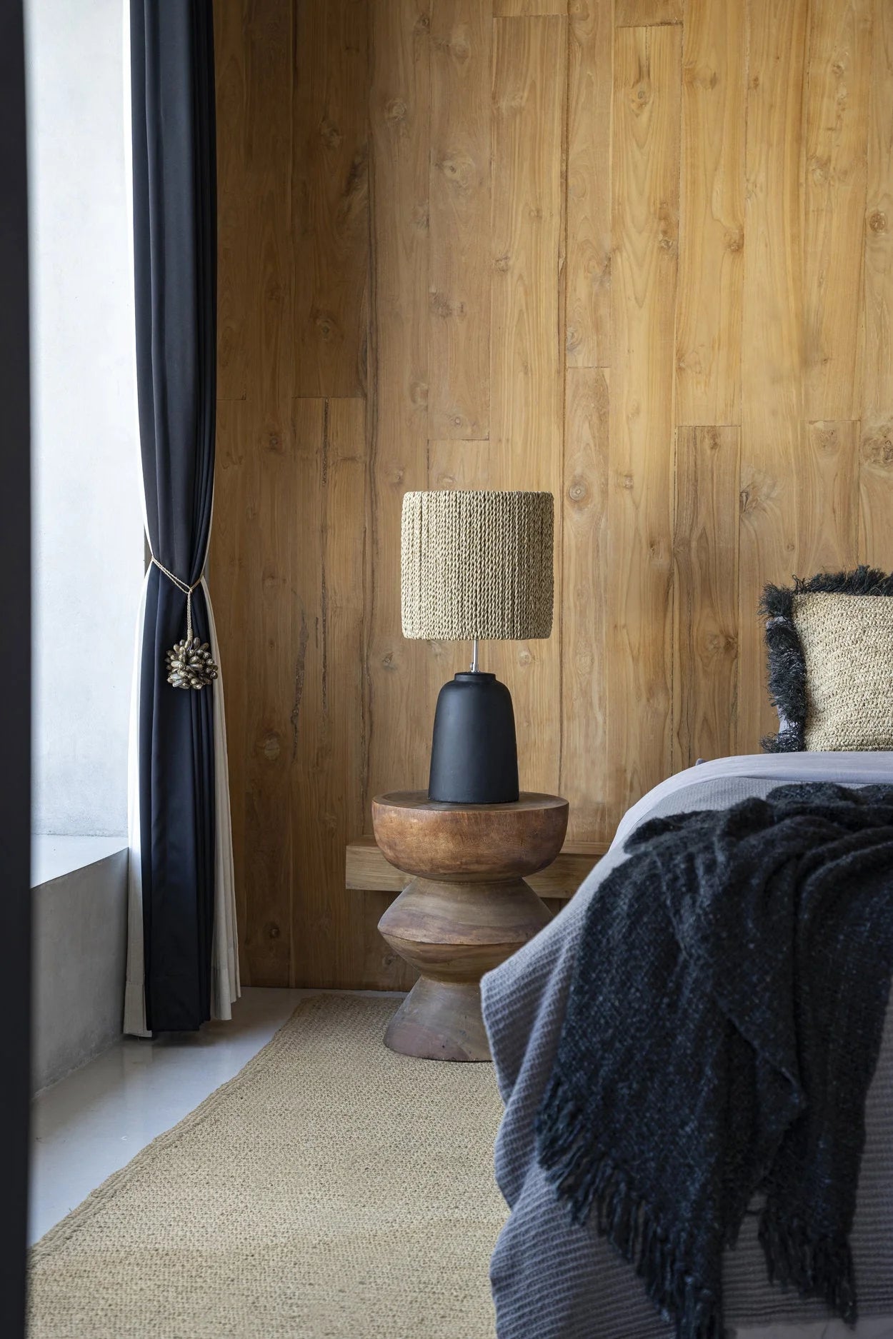 Abat-jour tissé sur une base sombre avec le tabouret sculptural en bois de Suar brun naturel