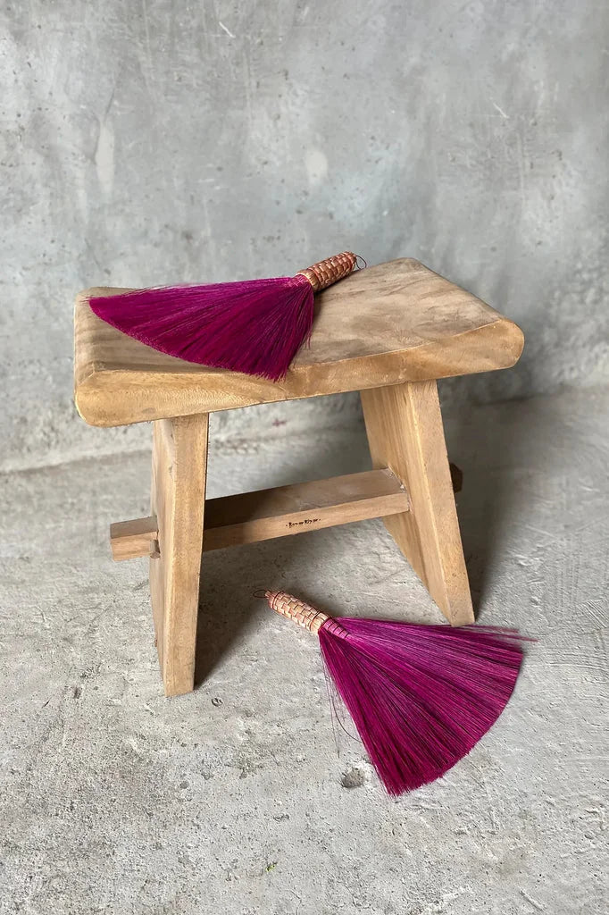 Deux balais en paille rose sur un tabouret en bois Le Tabouret Suar 50