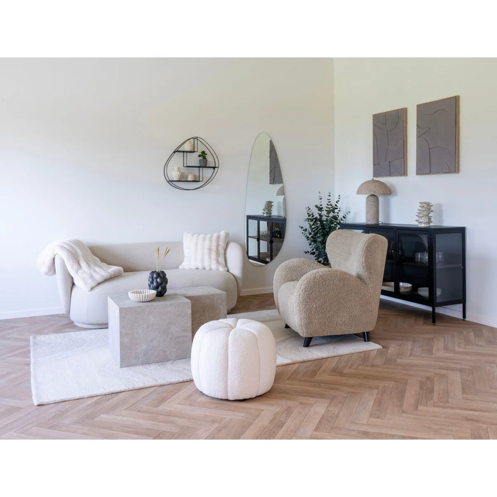 Fauteuil en peau de mouton beige moelleux avec contours arrondis et pieds noirs