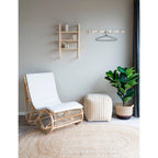 Chaise en osier avec coussins blancs sur tapis ovale en jute naturelle 140x200 cm