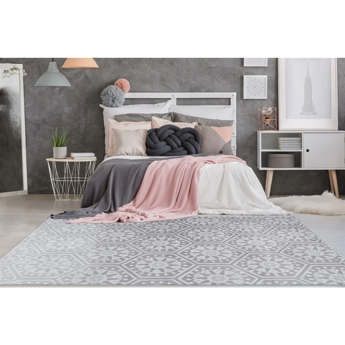 Lit avec tête de lit blanche, literie rose et grise, coussin nœud décoratif