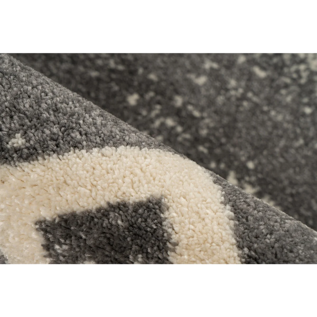 Vue rapprochée d’un tapis rectangulaire gris avec motifs ethniques et texture douce