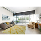 Tapis rectangulaire jaune doré à motifs losanges en relief dans un salon moderne avec canapé neutre