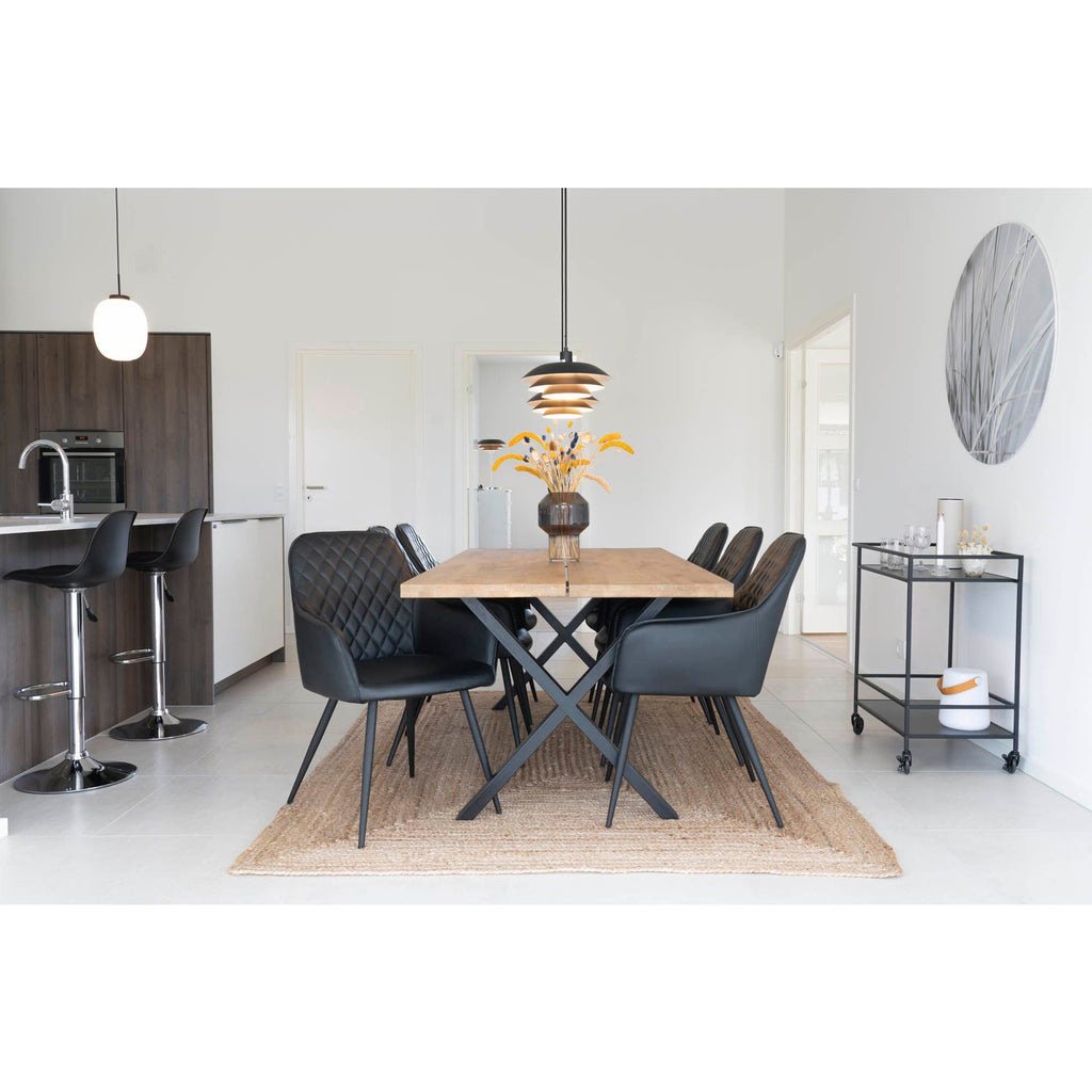Chaises de salle à manger en cuir quilté noir avec pieds métalliques autour d’une table en bois