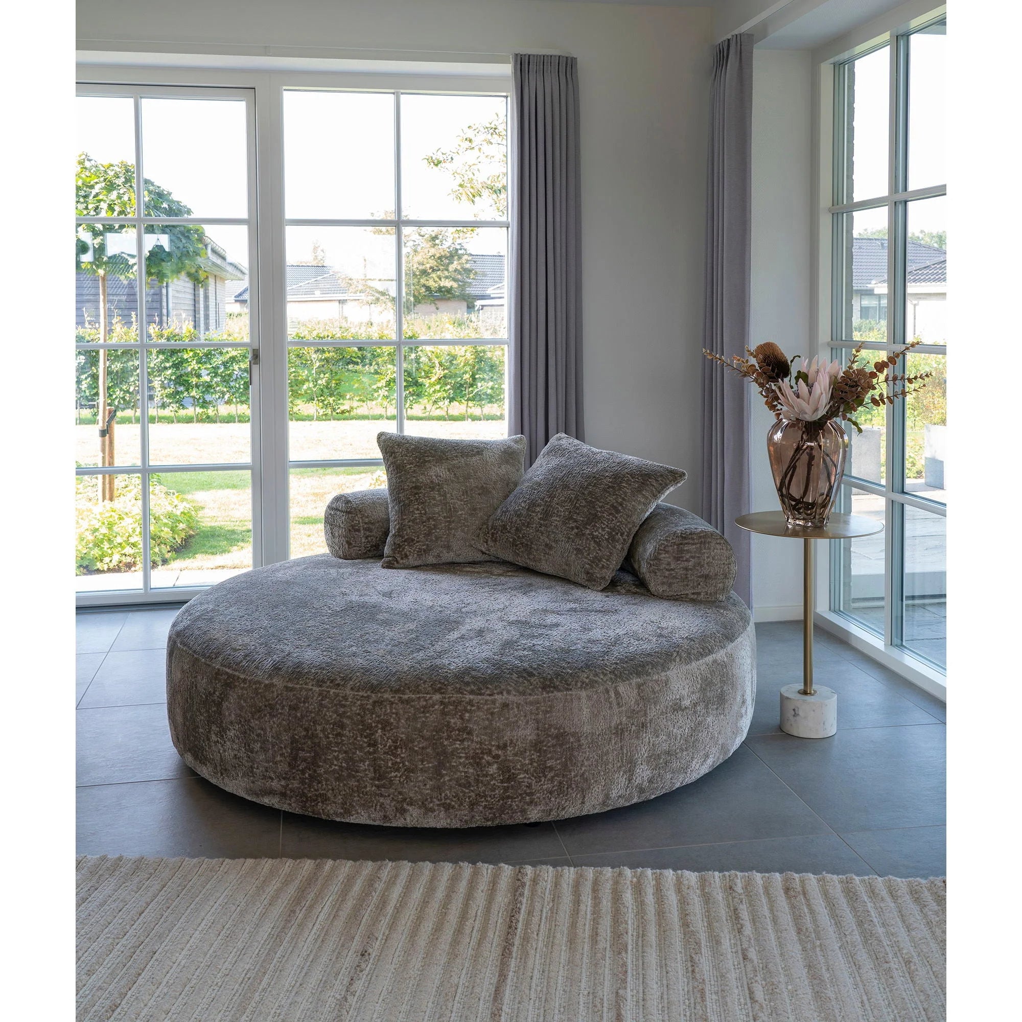 Canapé rond en tissu gris avec coussins, idéal pour décoration intérieure élégante