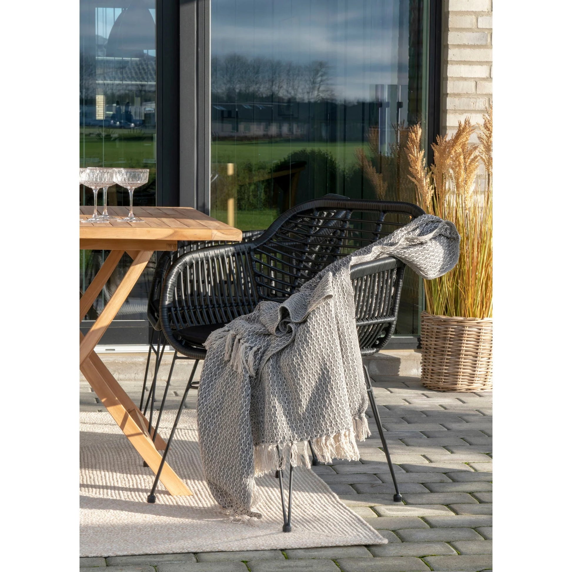 Chaise de patio en tissage noir avec jeté gris, tapis rectangulaire en matière recyclée