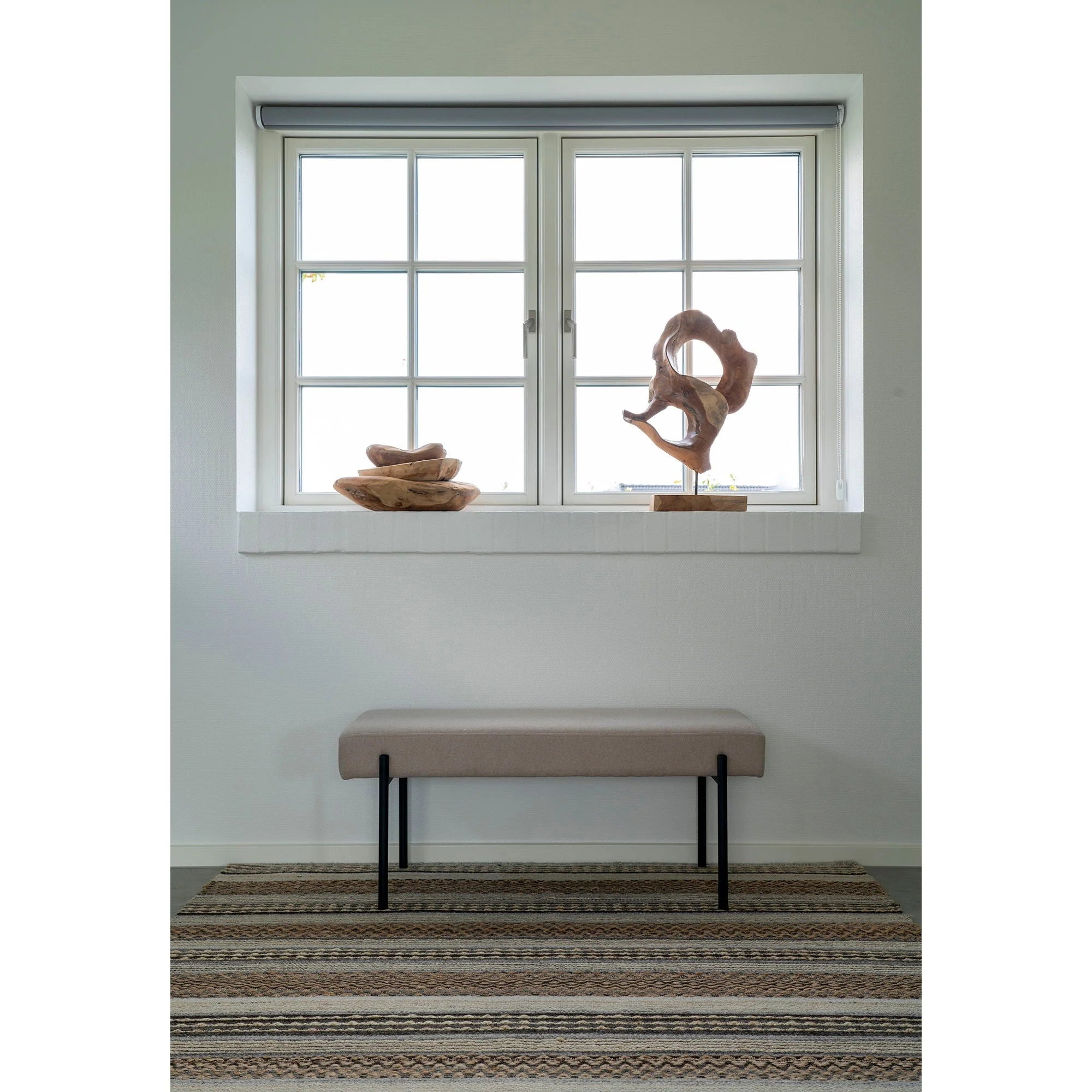 Banquette rembourrée avec pieds noirs dans le salon, Tapis rectangulaire en jute et laine