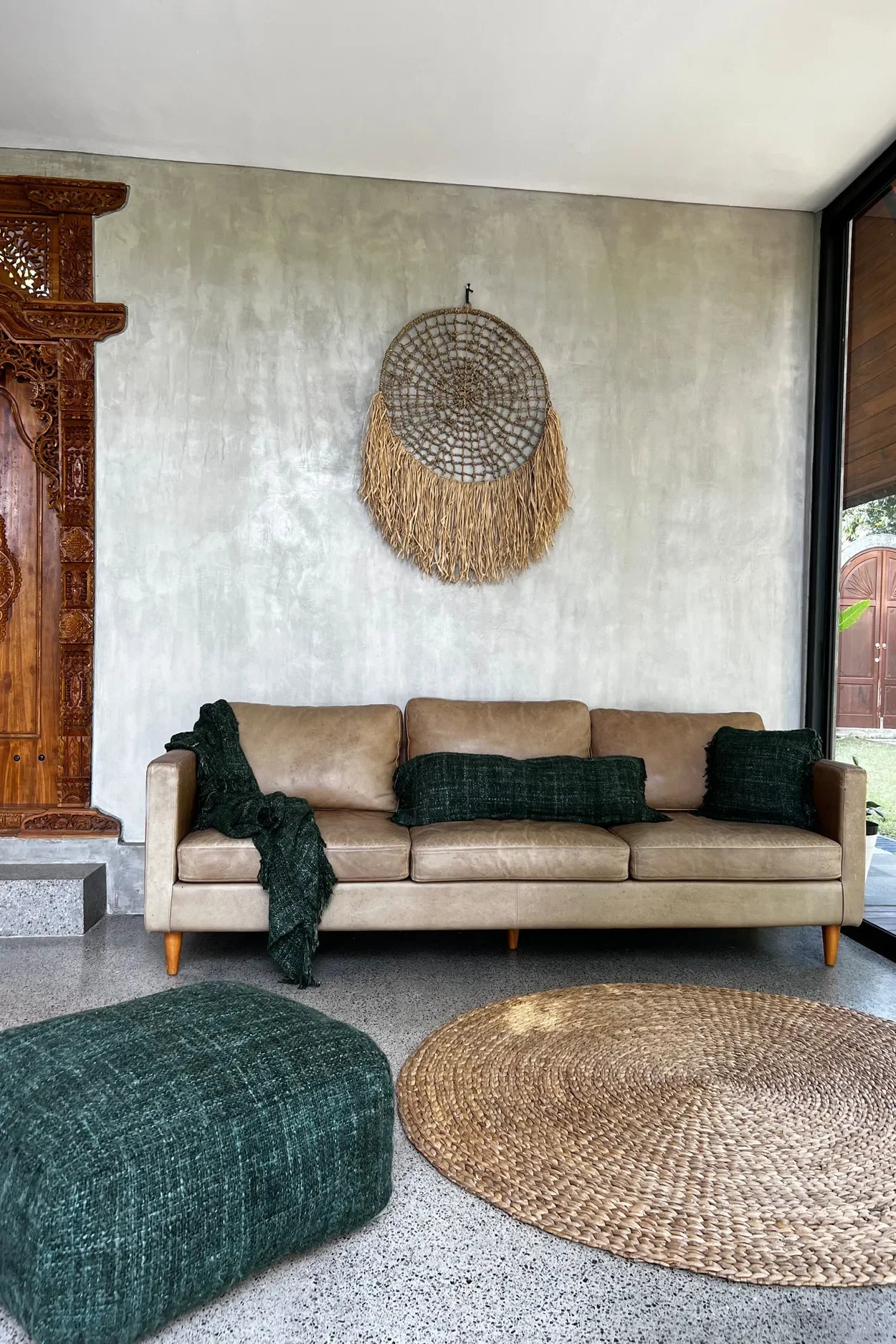 Canapé en cuir tan avec accents verts sur Tapis rond en jacinthe d’eau naturel 150 cm style bohème