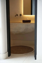 Intérieur de salle de bain moderne avec tapis rond en jonc de mer et coton blanc naturel
