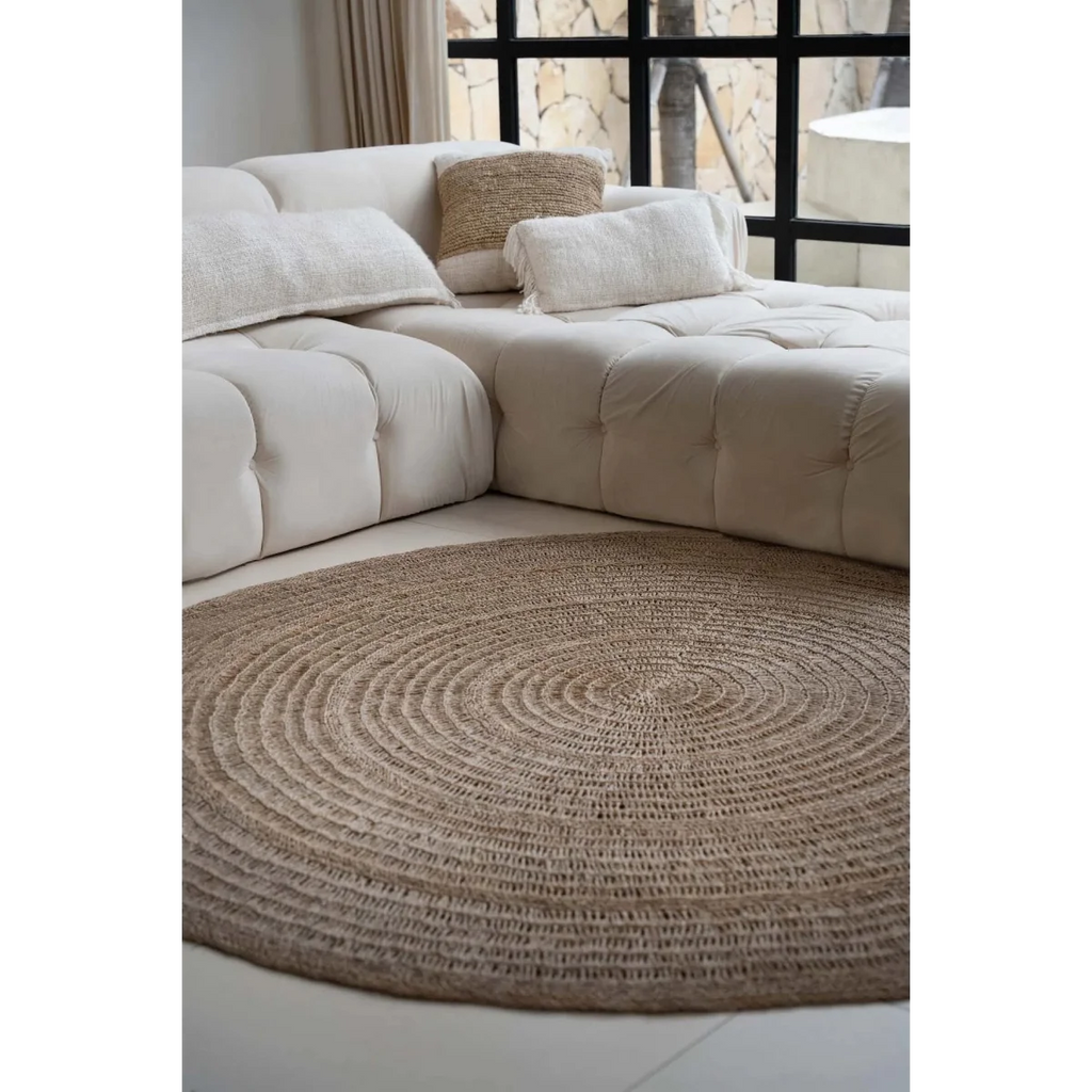 Canapé modulable beige avec coussins décoratifs et tapis rond en jonc de mer