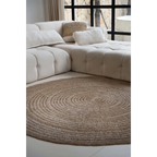 Canapé modulable beige avec coussins décoratifs et tapis rond en jonc de mer