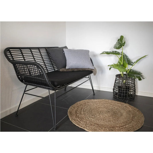 Canapé en rotin noir avec coussins sur le tapis rond en jute naturelle tressée Ø90 cm