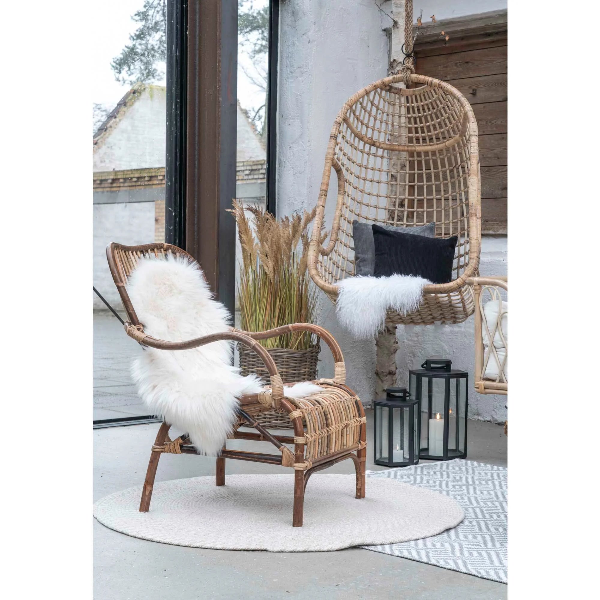 Chaise en osier avec plaid en fourrure blanche, tapis rond en jute beige sable