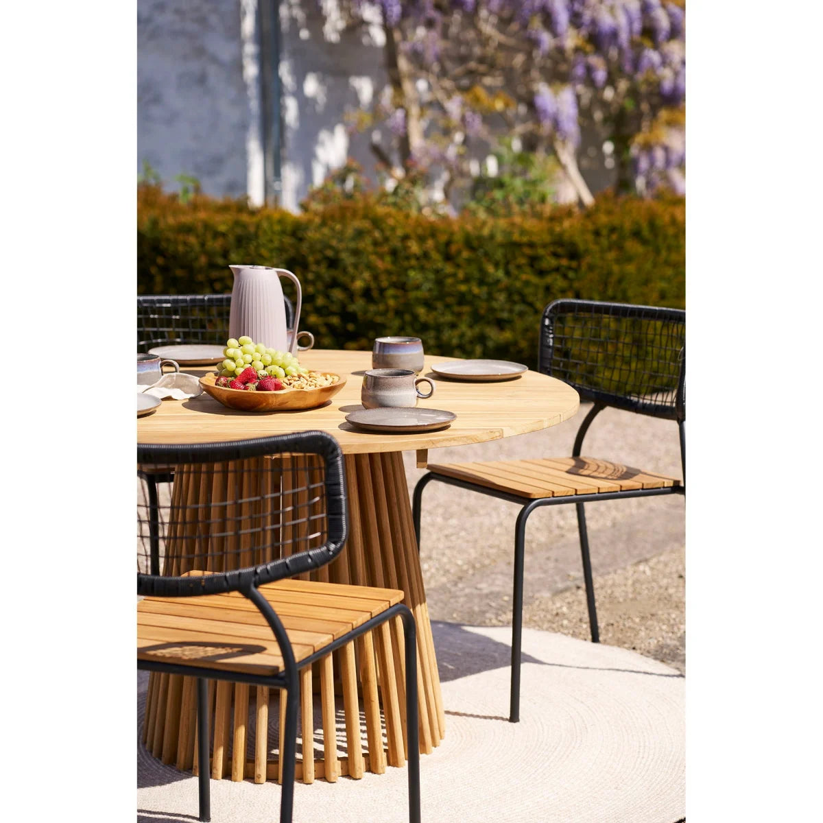 Table ronde bois naturel Ø180 cm, pieds bambou, chaises métal tressées sable recyclé