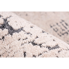 Zoom sur un tapis vintage écru et anthracite avec motifs géométriques abstraits