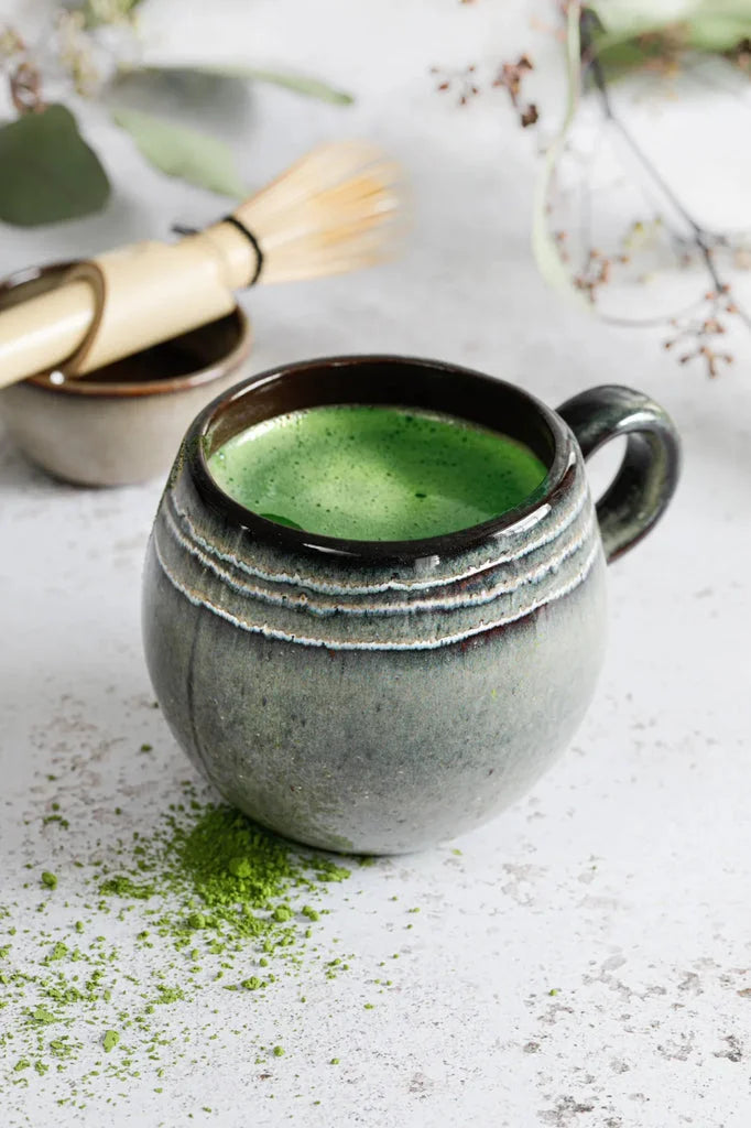 Tasse en céramique remplie de thé matcha vert dans lensemble La Tasse Comporta L