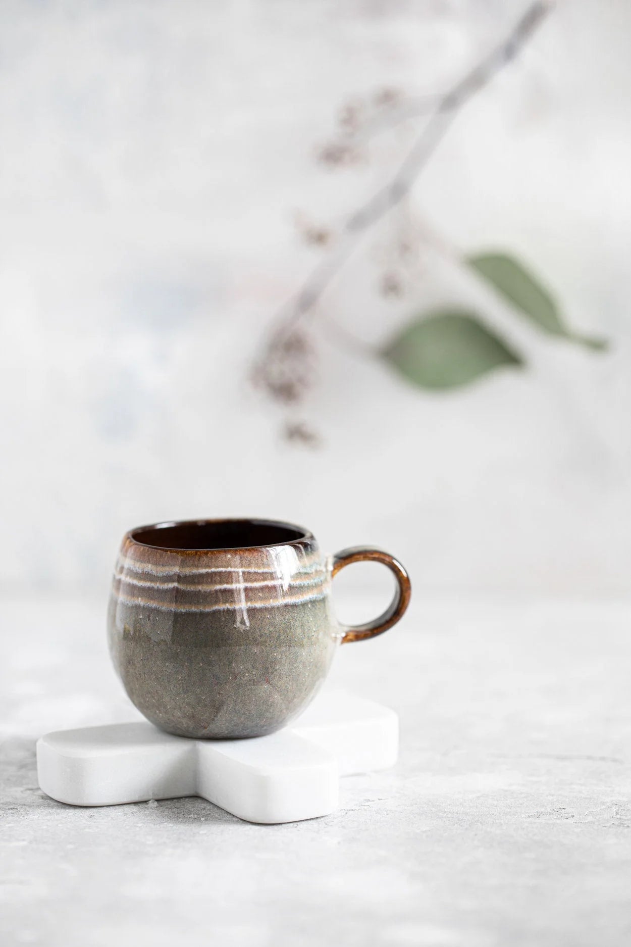 Tasse espresso artisanale en céramique vert sauge et brun, mug rustique sur coquetier marbre blanc