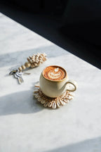 Tasse artisanale en céramique blanc cassé avec latte art et cacao