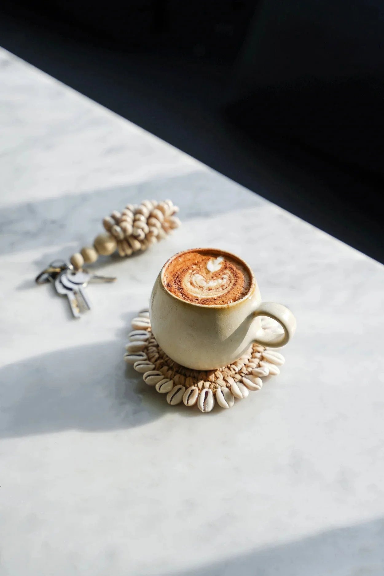 Tasse artisanale en céramique blanc cassé avec latte art et cacao
