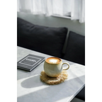 Tasses en céramique arrondies beiges avec latte art sur un dessous de tasse en rotin