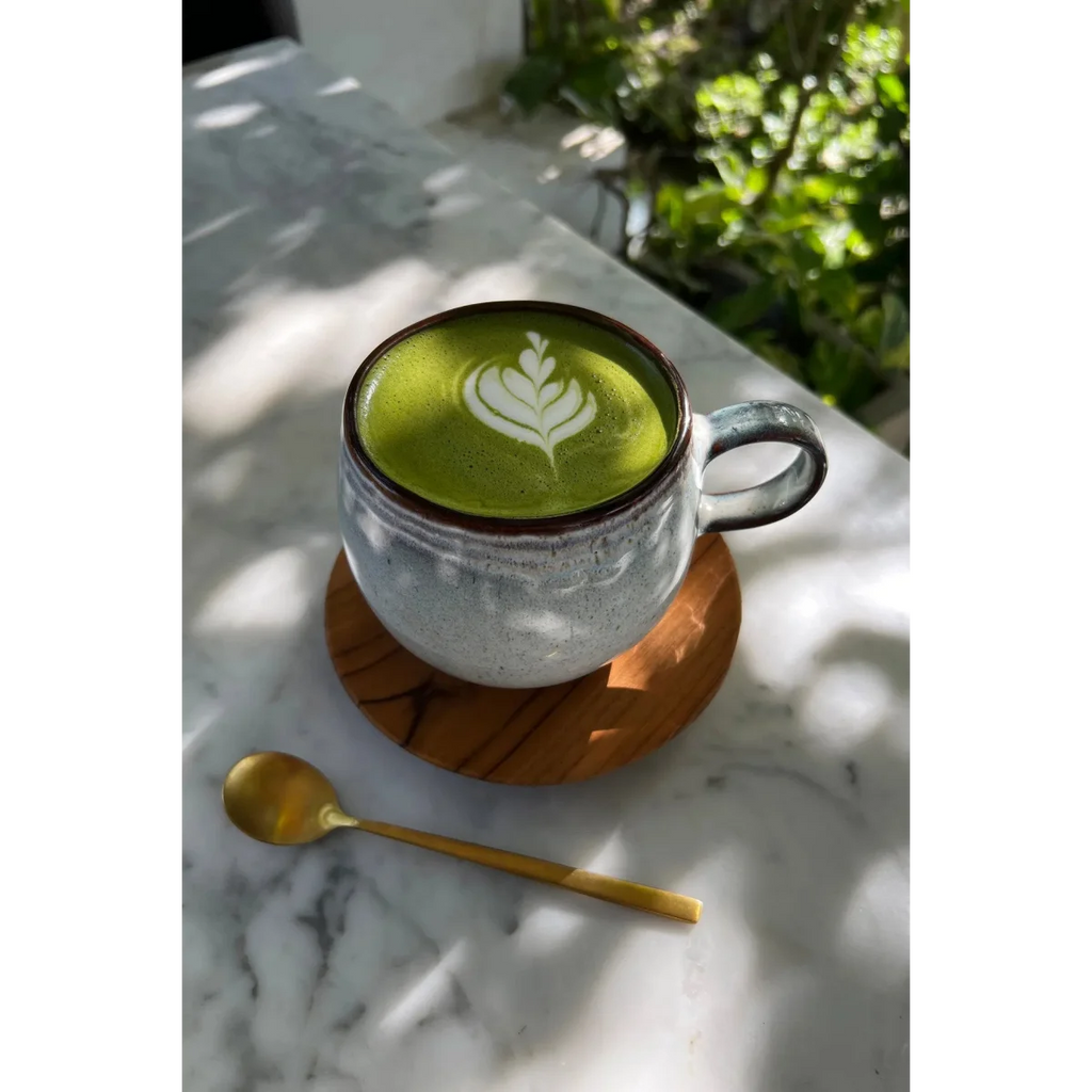 Tasse en céramique artisanale gris-vert à bandes texturées avec un matcha latte art