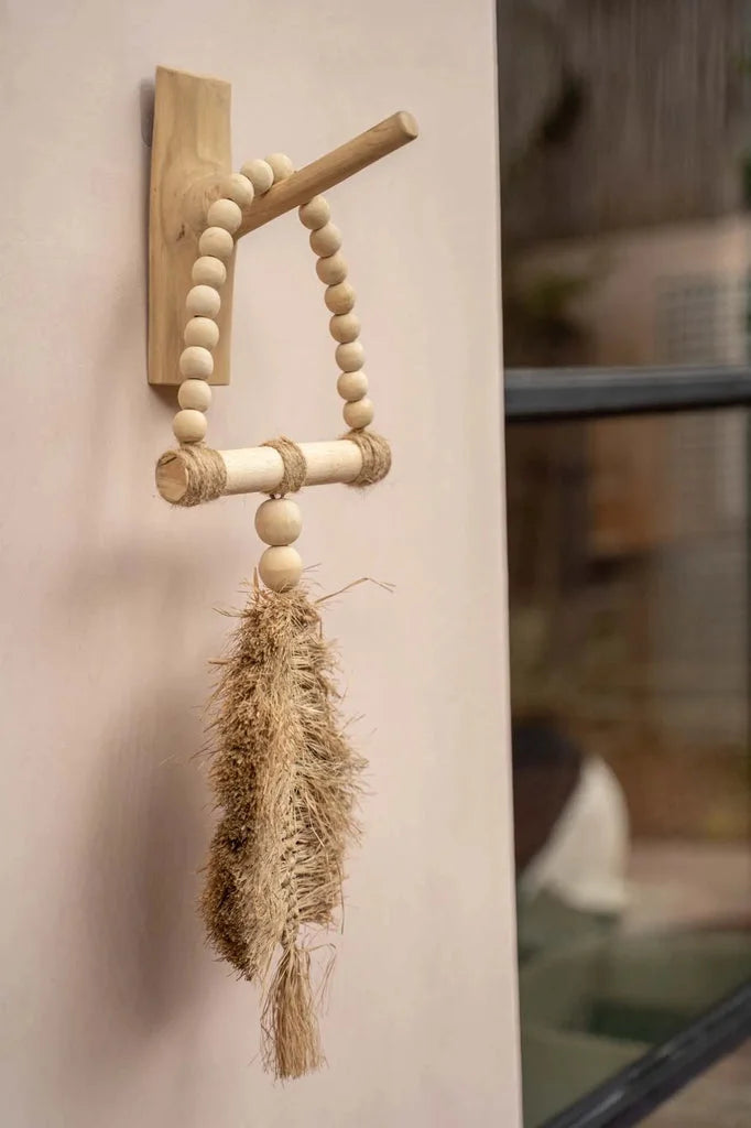 Suspension murale en bois avec perles et pompon.