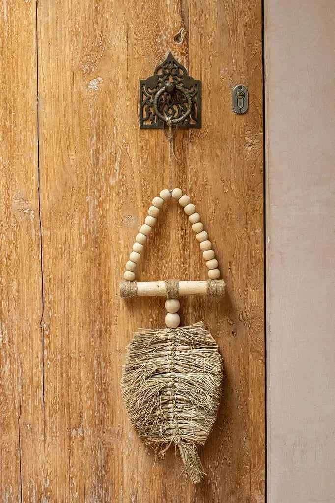 Porte en bois suspendue avec des perles et des fibres tissées.