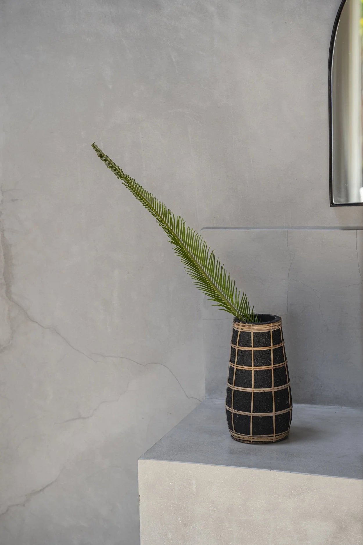 Vase cylindrique en terre cuite noir et rotin tressé avec une fronde verte