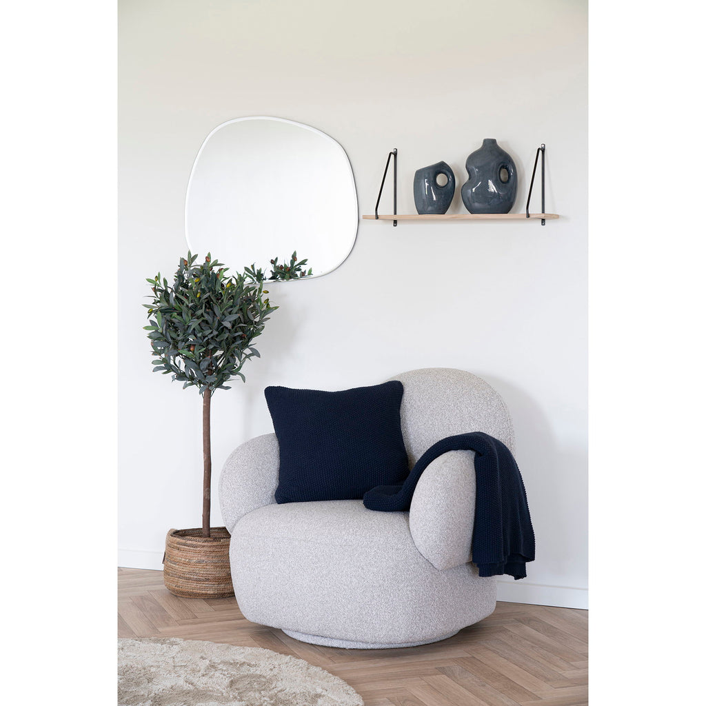 Fauteuil gris clair moelleux aux contours arrondis avec coussin bleu marine