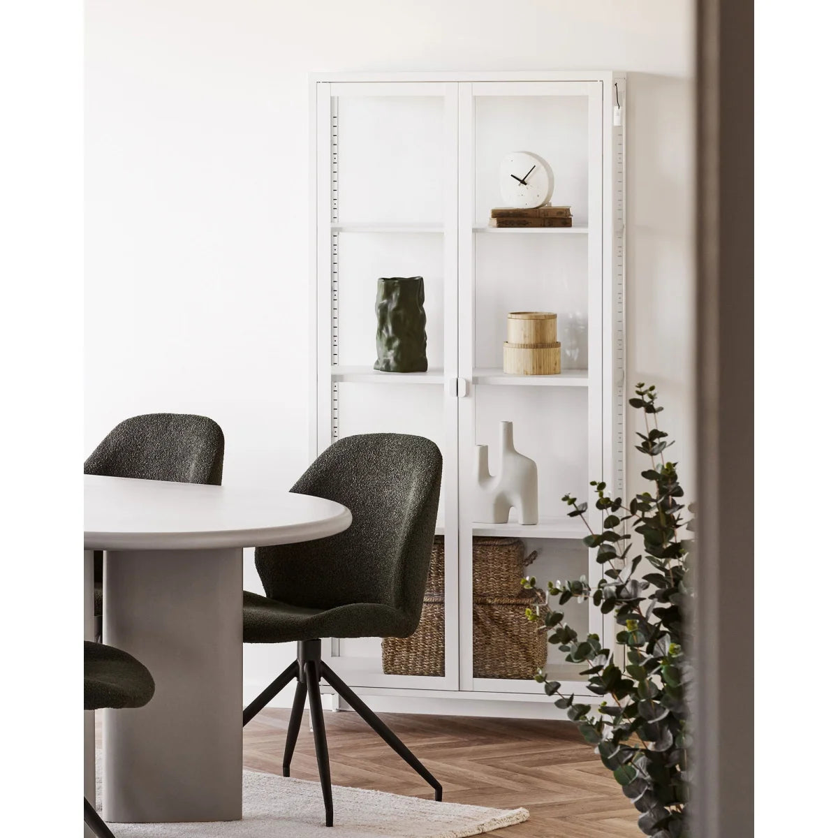 Vase décoratif en céramique vert olive finition mate dans une armoire moderne en verre