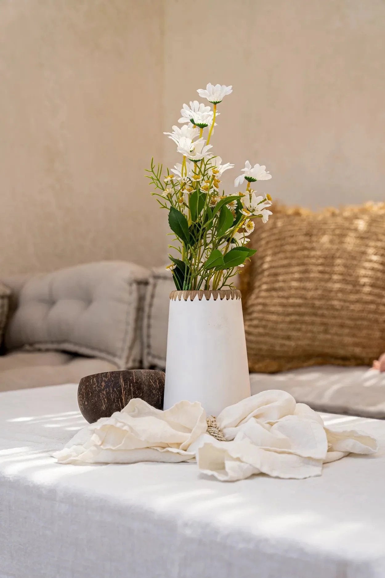 Arrangement floral de marguerites blanches dans un vase en terre cuite avec raphia