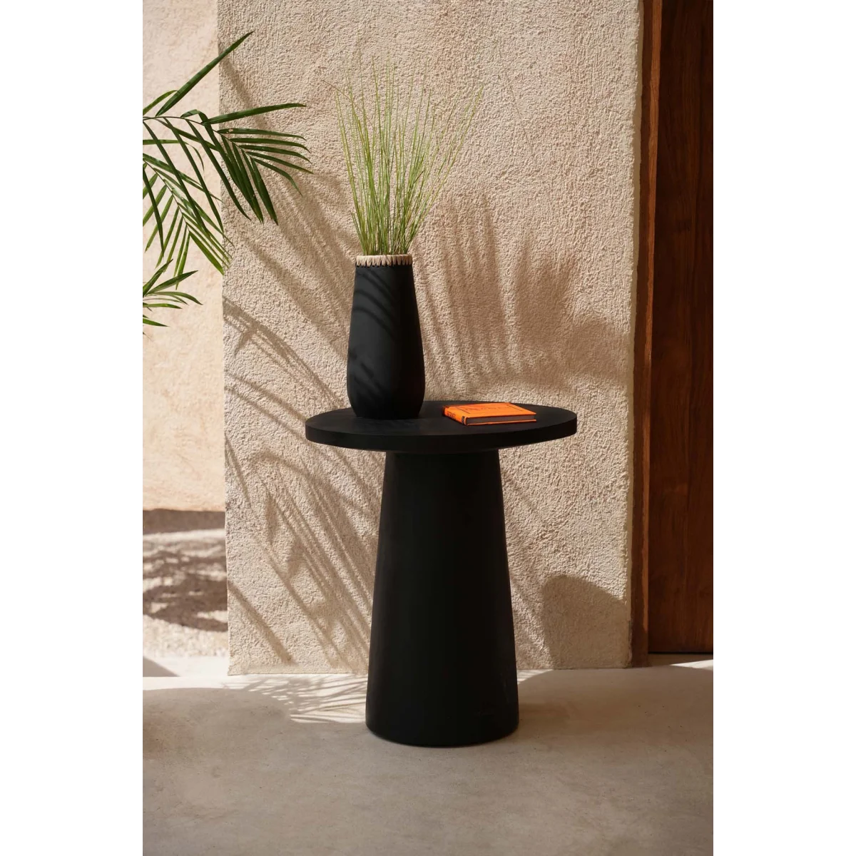 Table d’appoint en terre cuite noire avec vase décoratif et livre orange