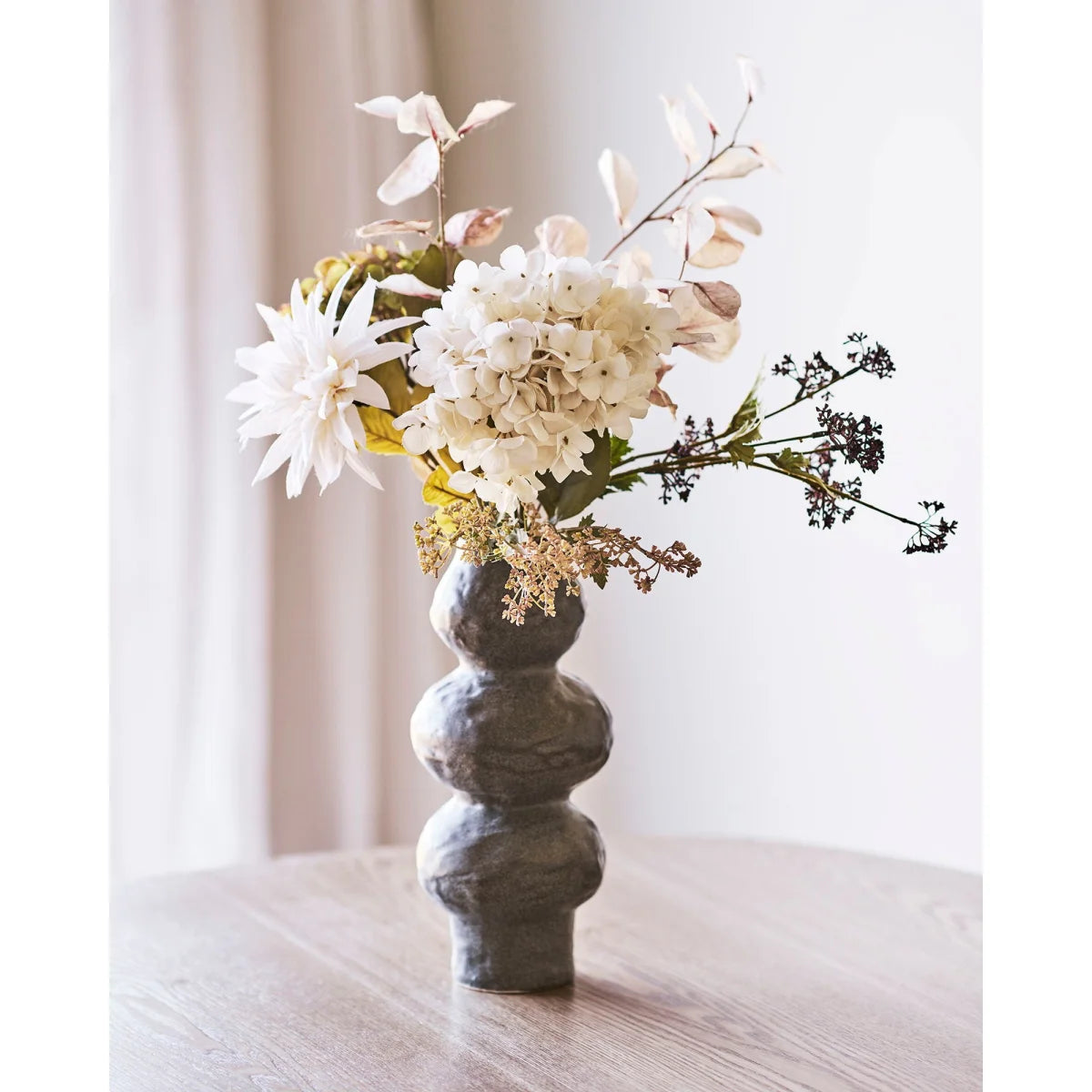 Vase organique en céramique mouchetée brun gris avec arrangement floral blanc
