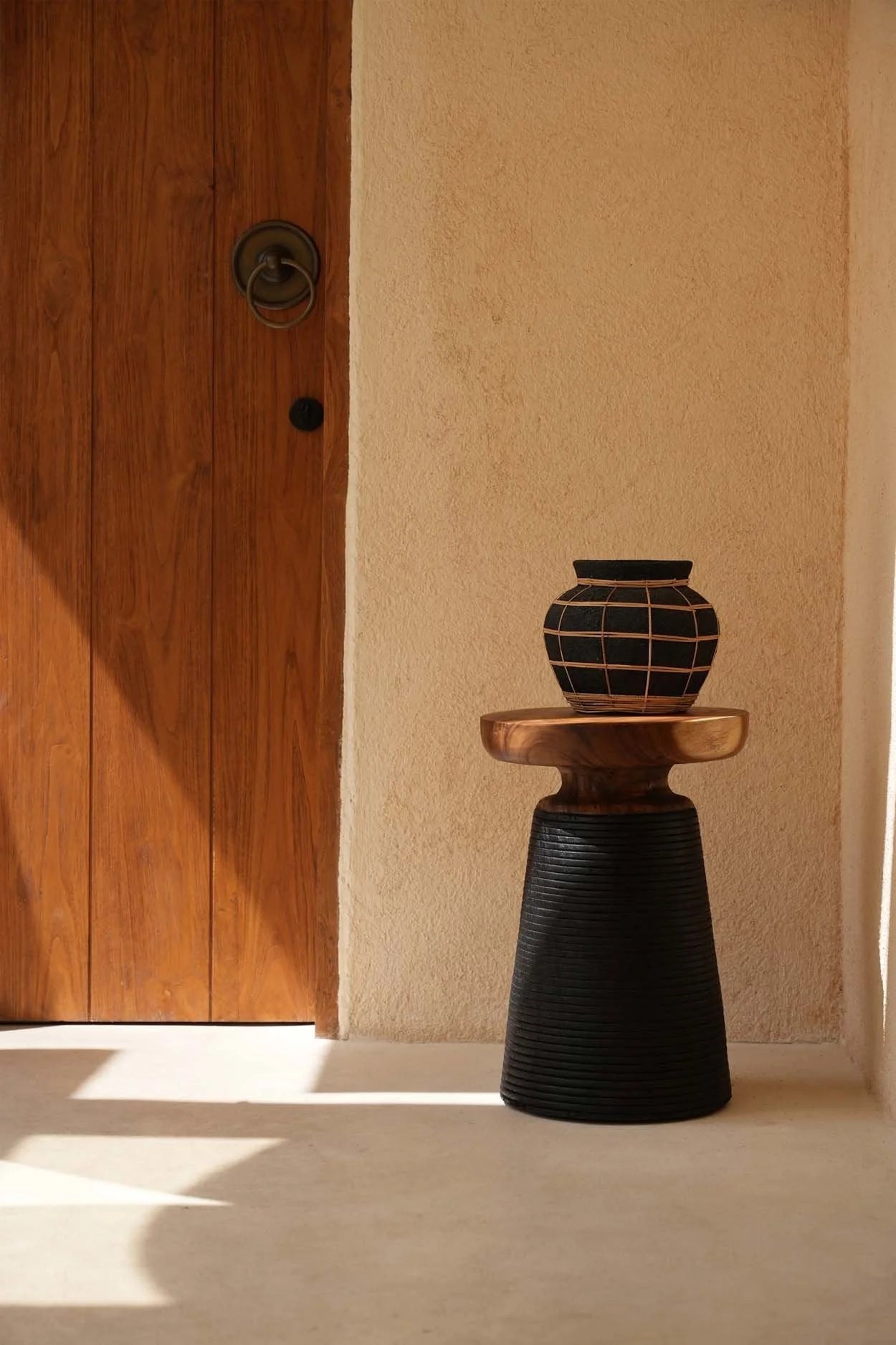 Vase rond noir en terre cuite avec détail en rotin sur support, décoration élégante