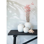 Vase rond en terre cuite beige avec texture, contenant des tiges florales séchées roses