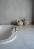 Vasque en terre cuite gris beige avec détail rotin et aspect béton brut dans une salle de bain
