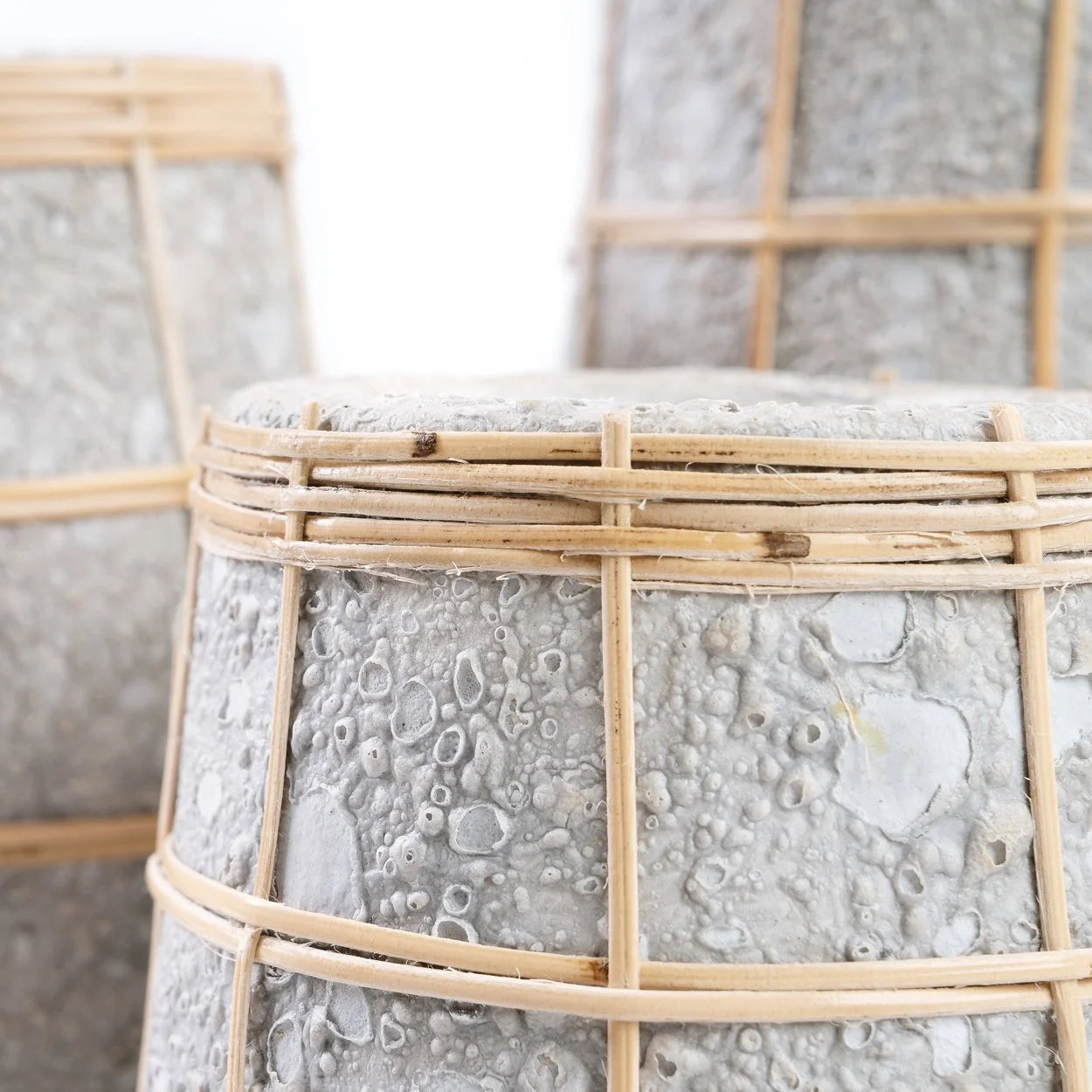 Vases en terre cuite gris avec treillis en rotin naturel et plantes dans des jardinières texturées