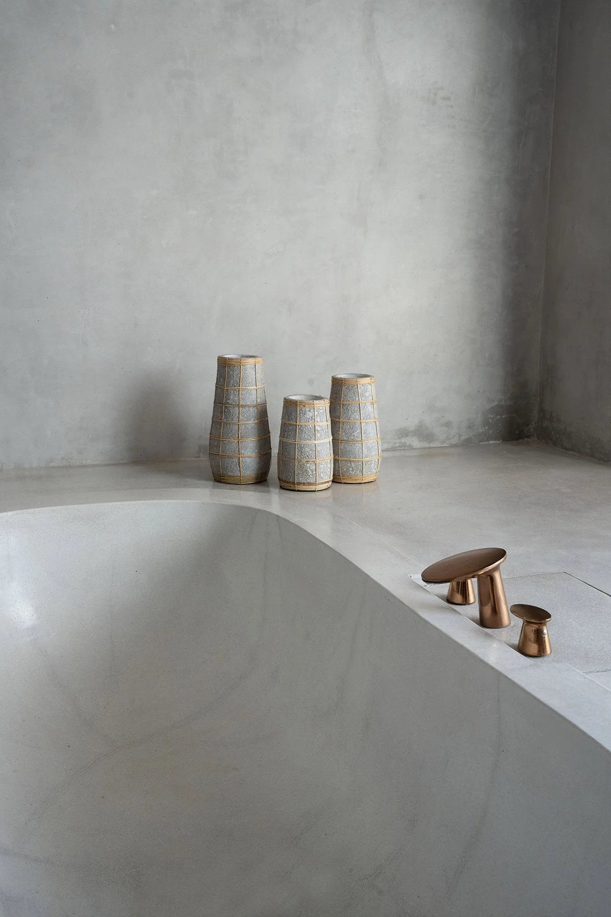 Trois vases en céramique texturée grise avec treillis en rotin naturel