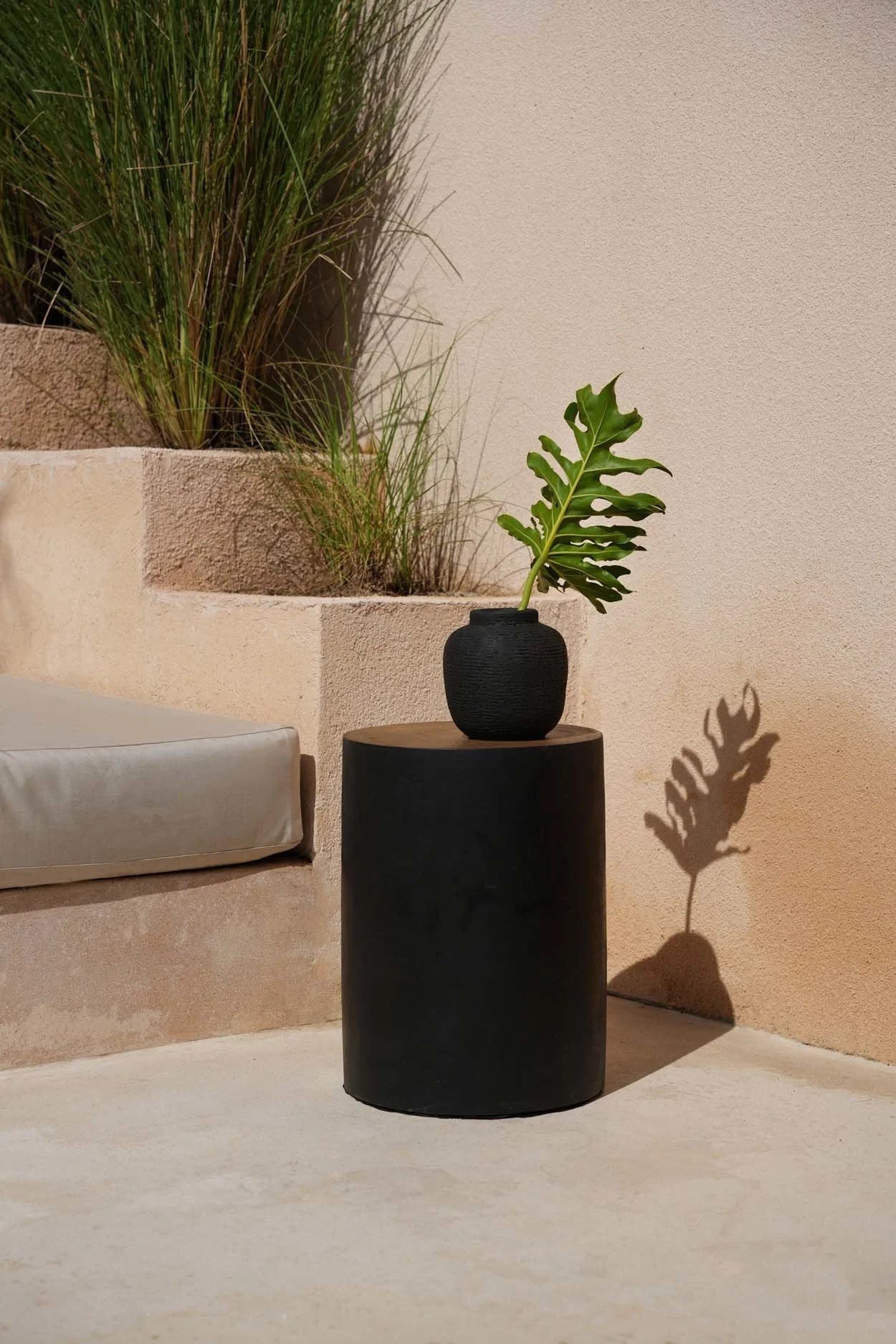 Table d’appoint cylindrique noir avec vase en terre cuite côtelée et feuille verte