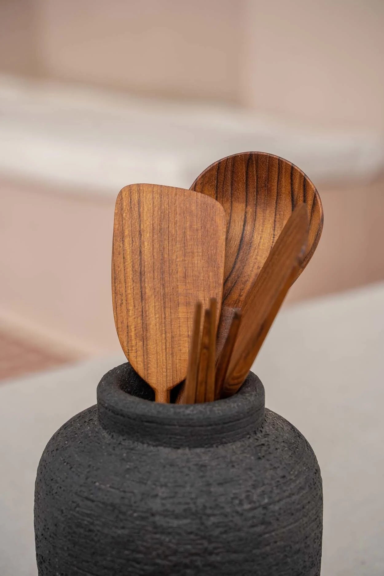 Vase en terre cuite noire à texture côtelée avec des ustensiles en bois