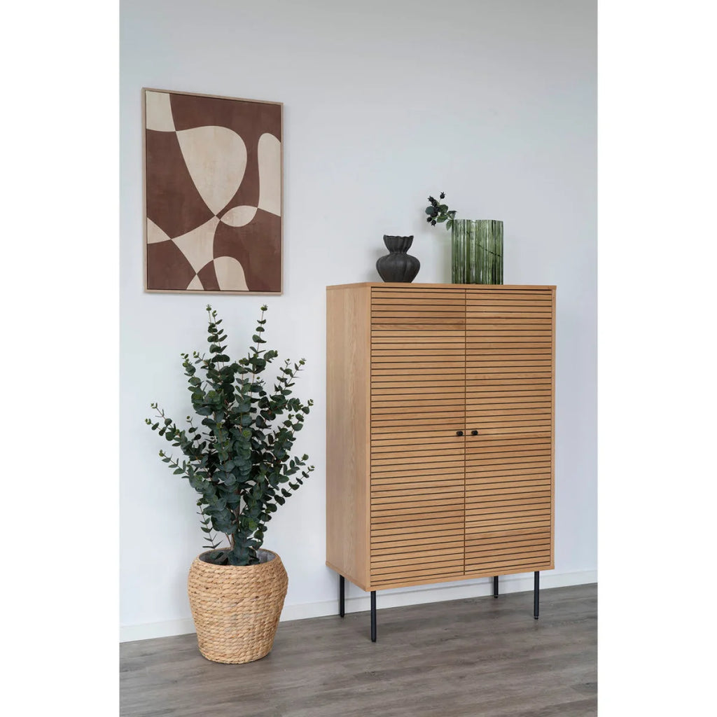 Vase en verre vert cannelé ondulé H26,5 cm sur meuble bois naturel