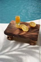 Plateau en bois avec tranches de citron et verre de jus d’orange en bord de piscine
